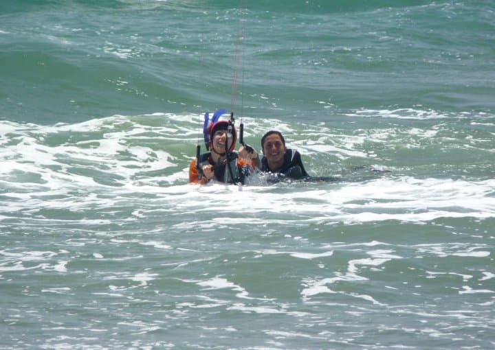 Instructor y alumno con arnés de kitesurf en el agua durante una clase de Fredoom Kite School