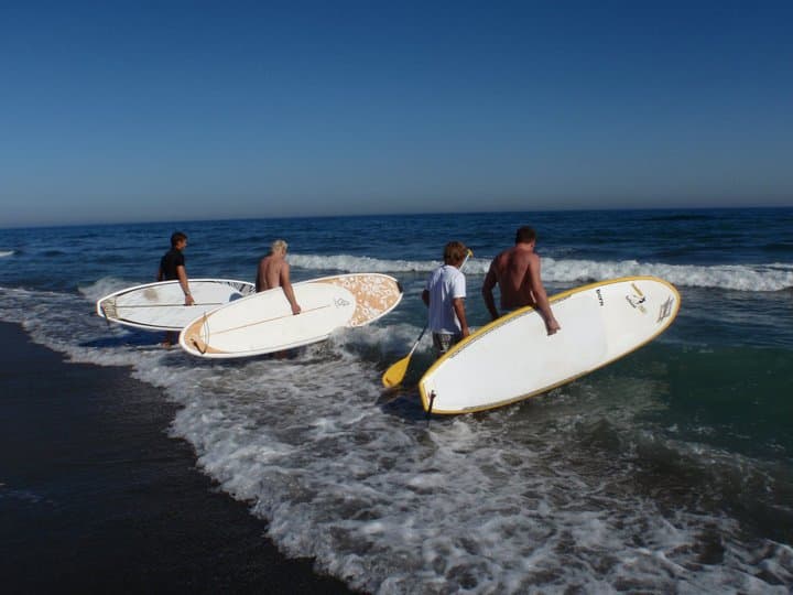 Grupo con tablas de paddle surf entrando al agua en una sesión de Fredoom Kite School