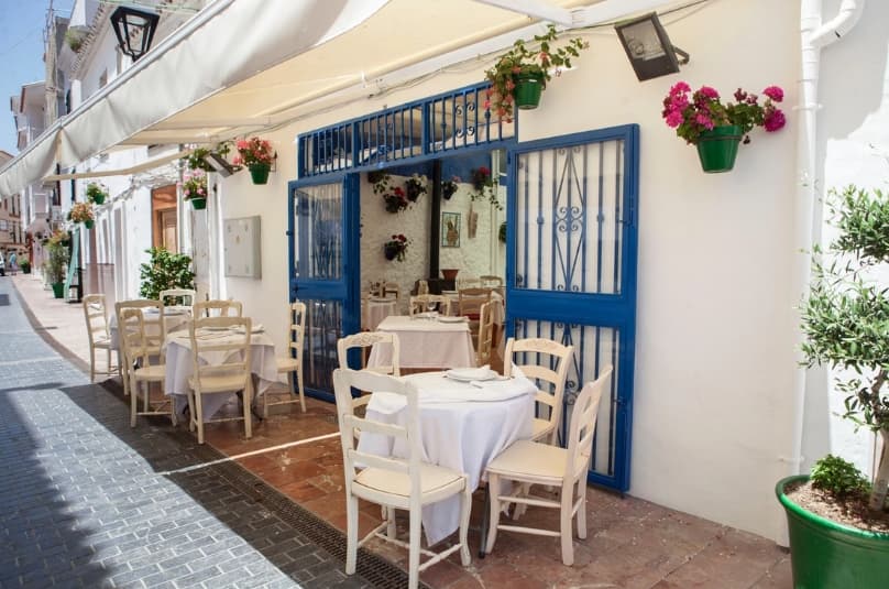 Terraza con mesas en una calle blanca del casco antiguo de Estepona.