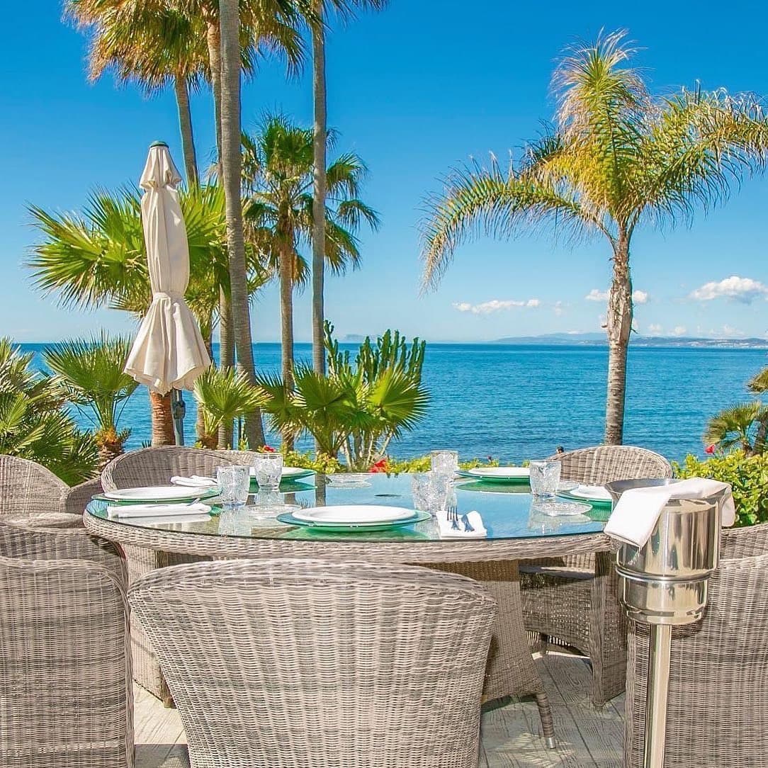 Mesa puesta en una terraza a pie de playa en Estepona, con el Mediterráneo al fondo