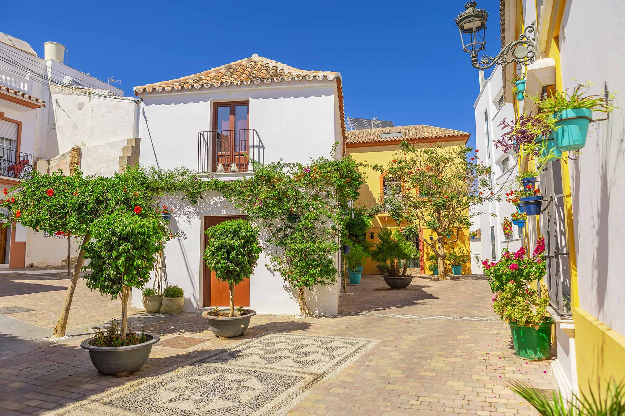 Placita empedrada del casco antiguo de Estepona con fachadas blancas y amarillas y macetas colgadas