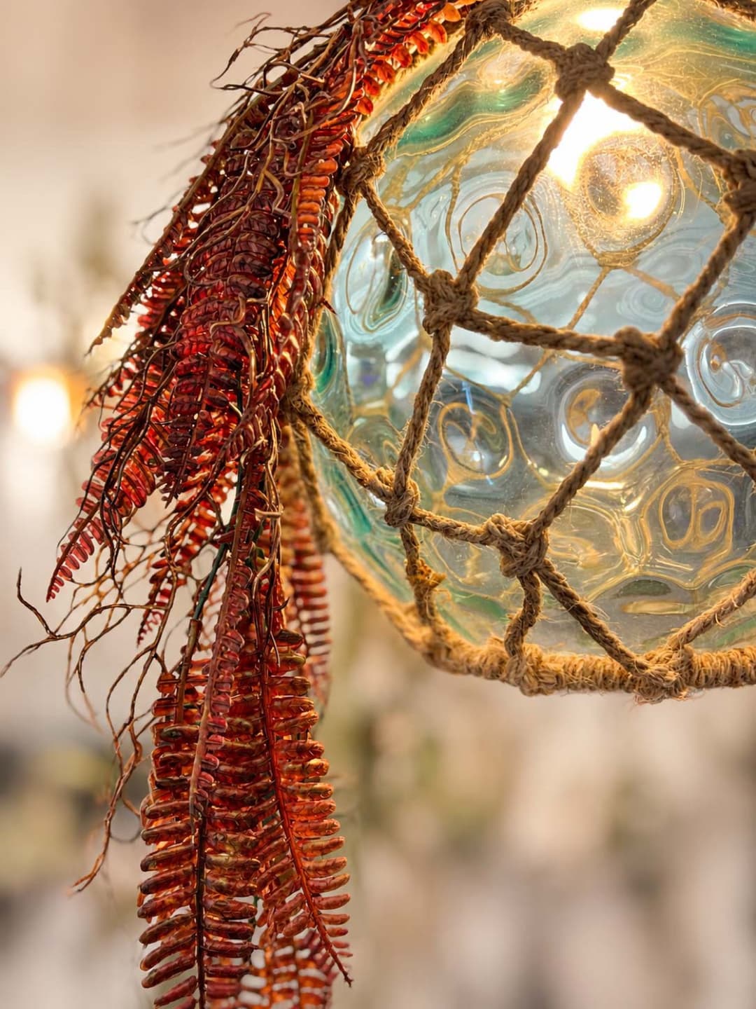 Lámpara de boya de cristal envuelta en red de esparto con coral seco, en el Restaurante La Palma