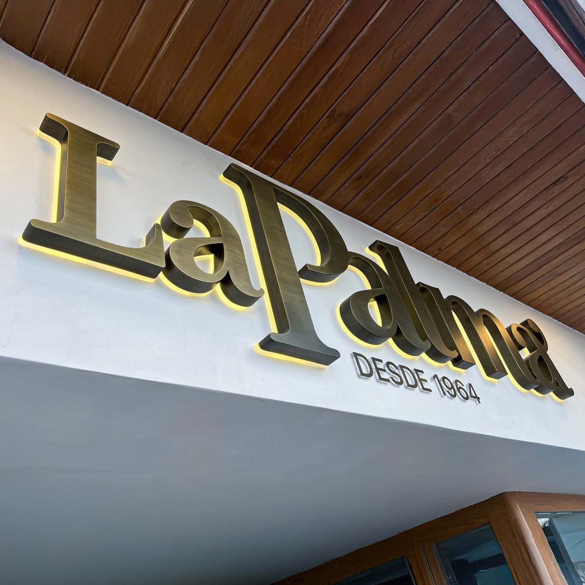 Rótulo luminoso de La Palma con la leyenda «desde 1964», en el techo de madera del restaurante