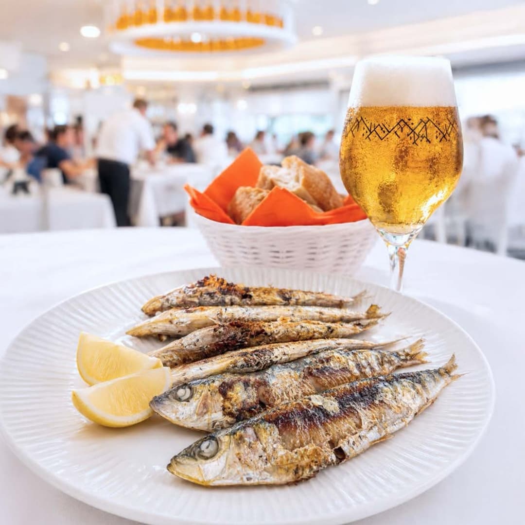 Sardinas a la brasa con limón y pan en el Restaurante La Palma, con el comedor al fondo