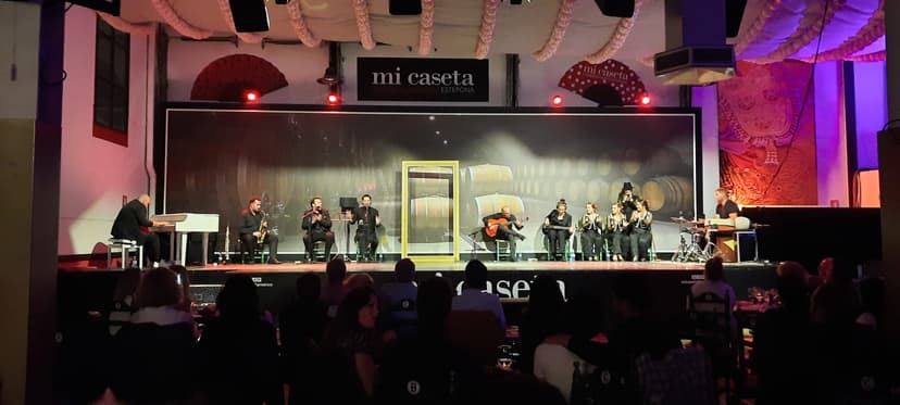 Coro y banda en directo sobre el escenario de Mi Caseta, Estepona, con el público en la sala