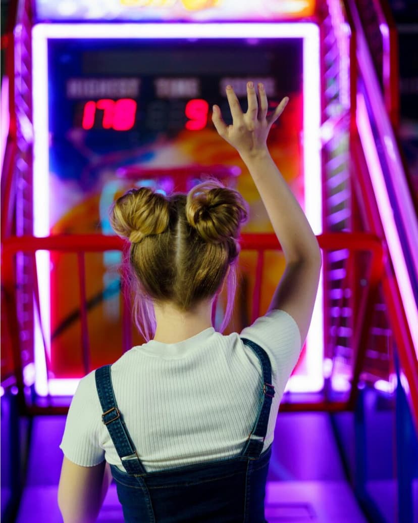 Chica jugando a una máquina arcade de baloncesto en Miroko Park