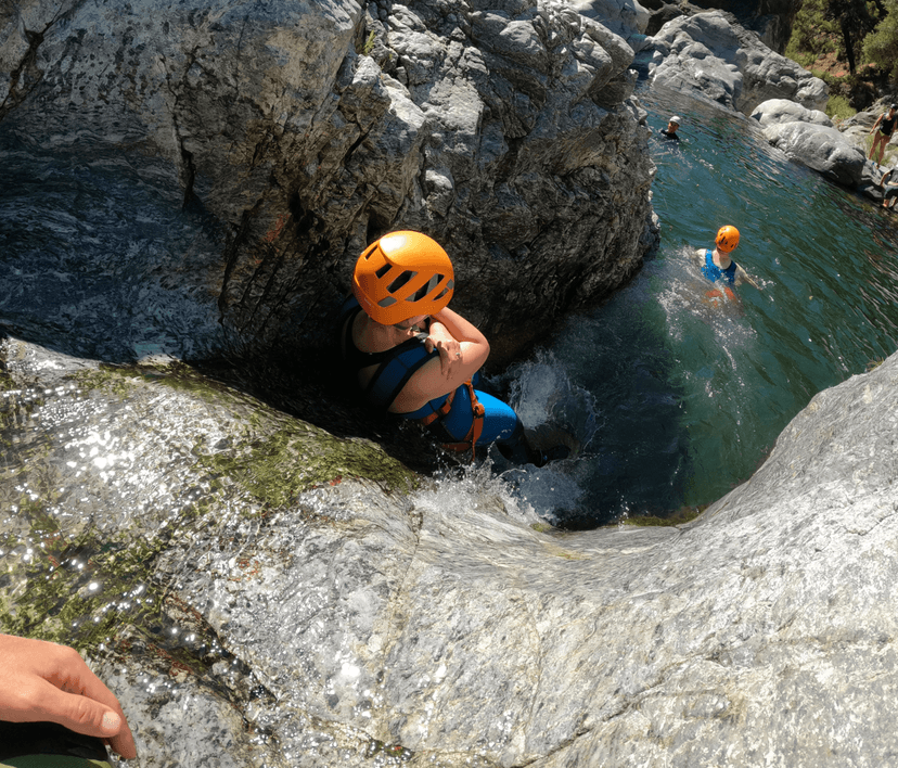 Participante con casco descendiendo por una poza de barranquismo en la Sierra Bermeja, Estepona