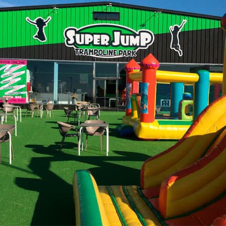 Terraza de Super Jump con mesas junto a la fachada del parque de camas elásticas