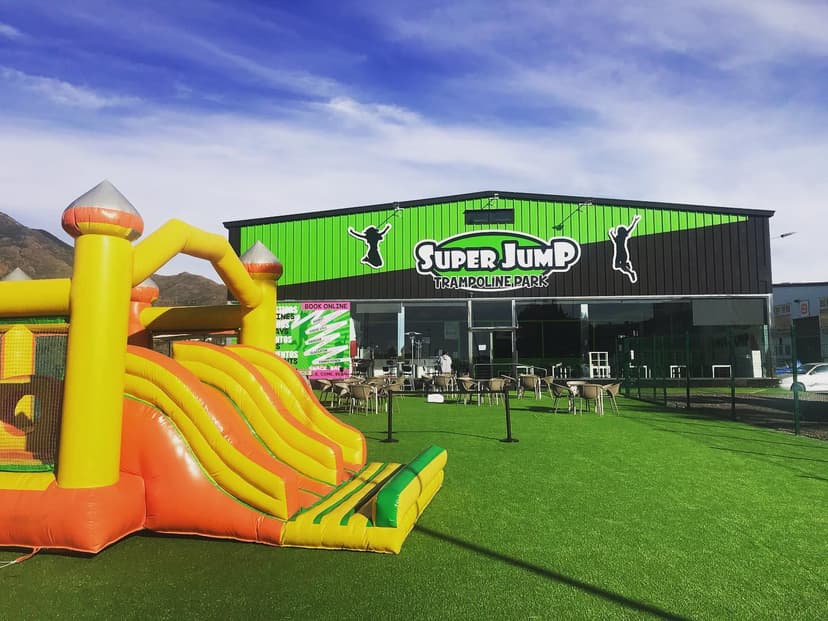 Fachada y terraza exterior de Super Jump Trampoline Park en Estepona, con el cartel del local y un castillo hinchable