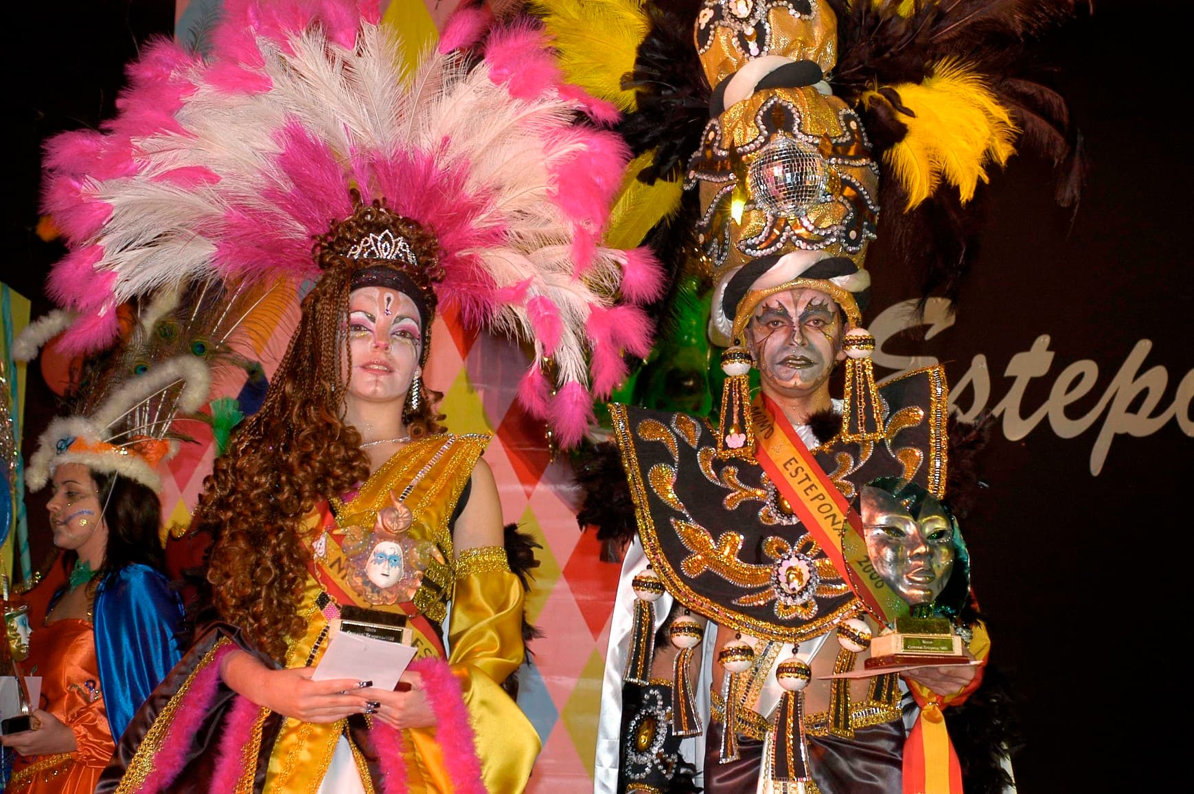 Reyes del Carnaval de Estepona con trajes de plumas sobre el escenario