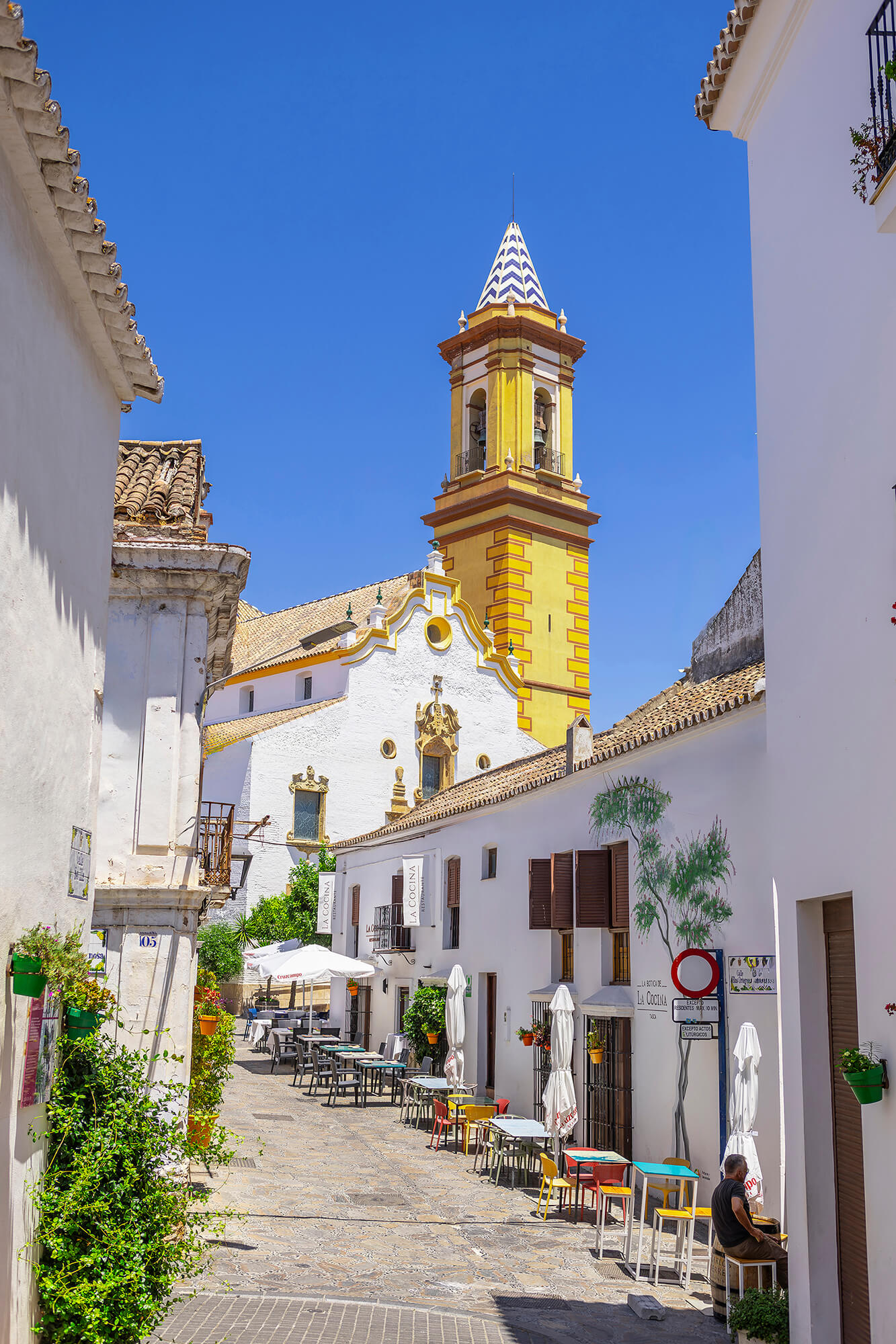 Calle del casco de Estepona con el campanario de la iglesia Los Remedios al fondo.